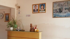 A reception area with a reception desk, framed photos on the wall, a clock, and a painting. - Both Bopha Angkor (Siem Reap)