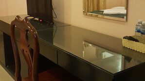 A hotel room with a long, dark wooden desk, a chair, a flat-screen TV, a mirror, and a small table with a decorative item. - Both Bopha Angkor (Siem Reap)