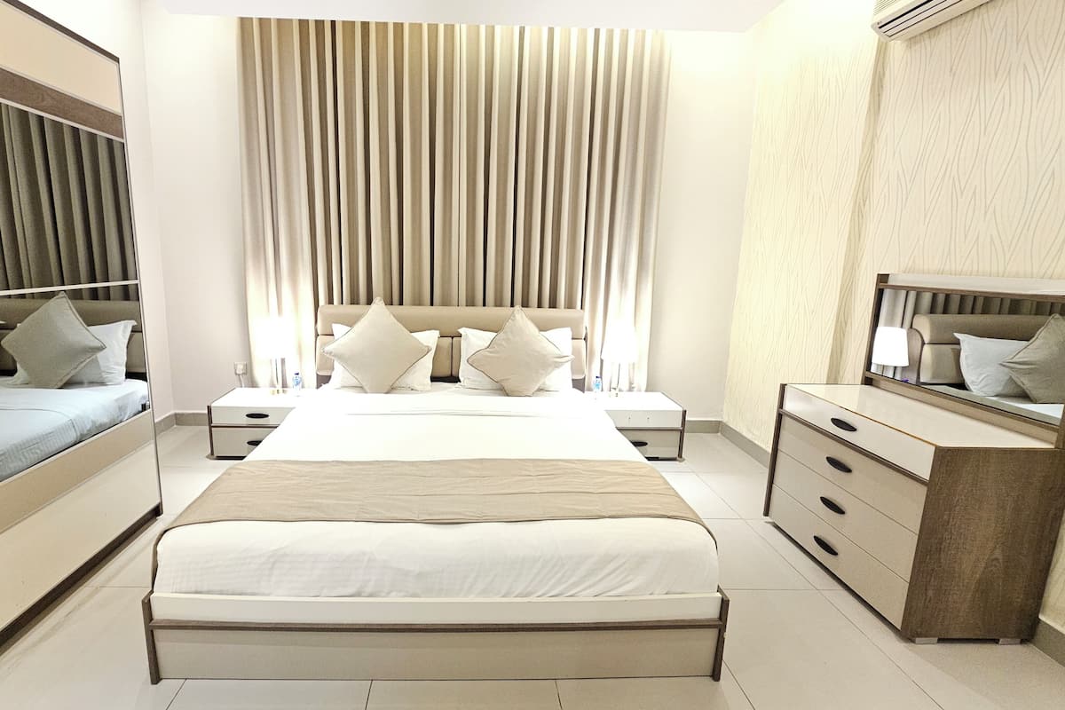 Ein modernes Hotelzimmer mit einem großen Bett, einem Kleiderschrank, einem Schminktisch und einem Spiegel.
