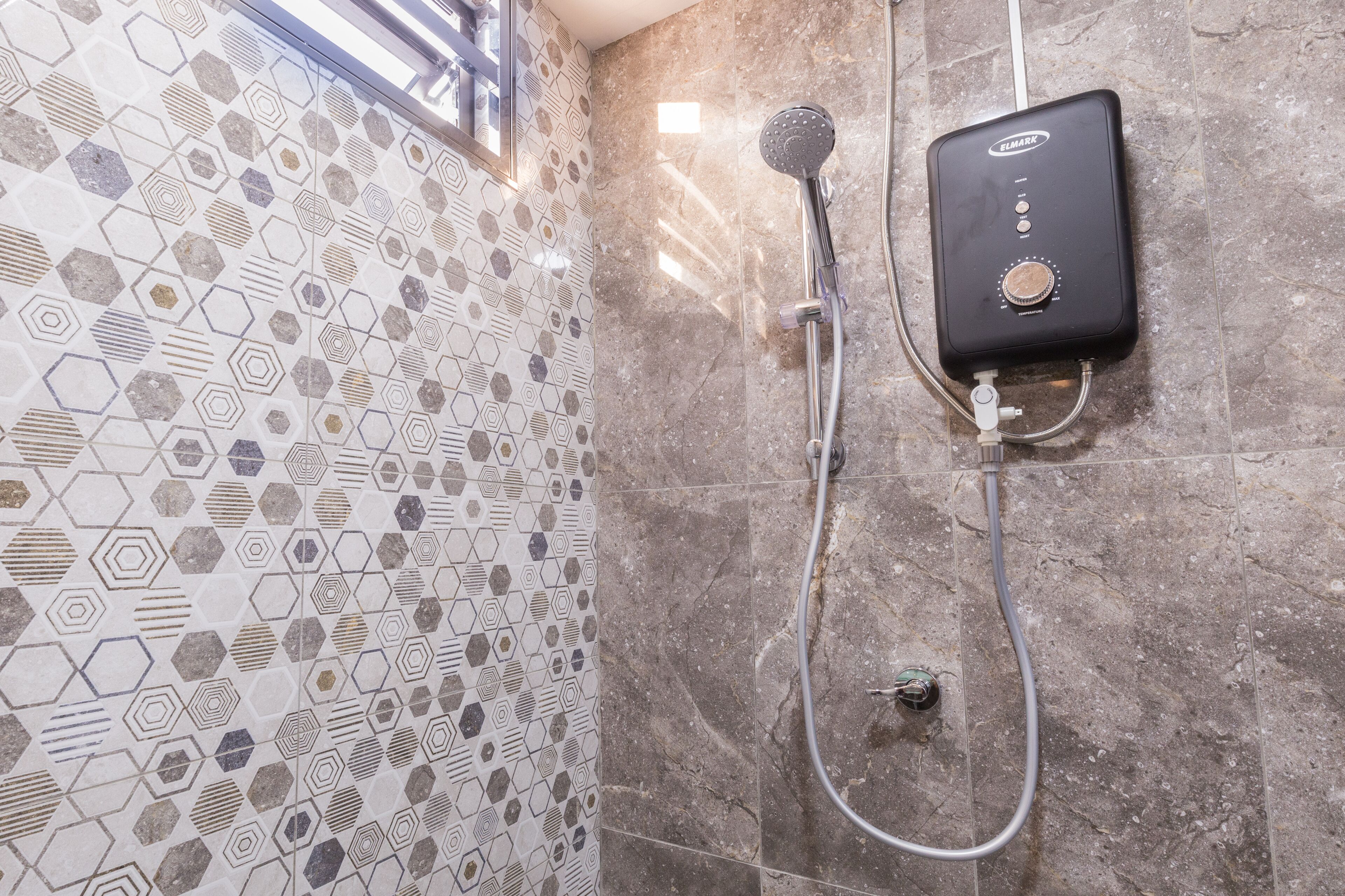 A shower area with a handheld showerhead and a wall-mounted control unit.