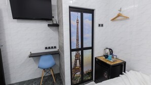 A hotel room with a bed, a desk with a chair, a TV mounted on the wall, a wooden hanger, and a small table with a kettle and cups. - Lee Luxury Home USM Penang (George Town)