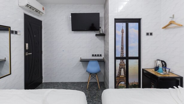 A hotel room with a bed, a desk, a chair, a TV, a wardrobe, and a view of the Eiffel Tower. - Lee Luxury Home USM Penang (George Town)