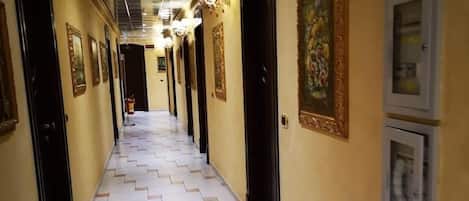 Un pasillo de hotel con piso estampado, puertas y obras de arte en la pared.