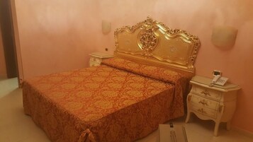 Un dormitorio con una cama grande, cabecera decorada, mesitas de noche y un teléfono.