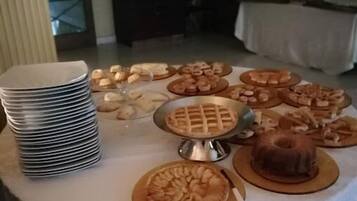 A buffet table with various baked goods and a stack of plates.
