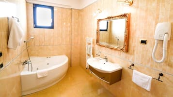 Un baño con bañera, lavamanos, espejo y toallero.