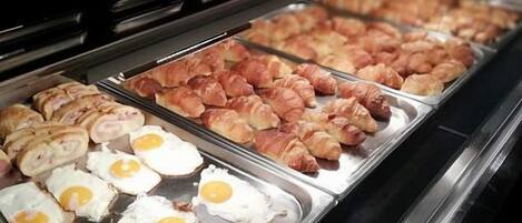A buffet with various food items including eggs, croissants, and pastries.