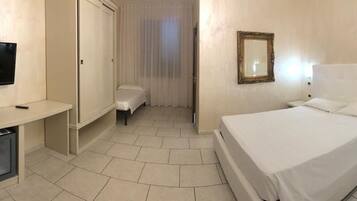 Une chambre d’hôtel comprenant un lit, des tables de chevet, une télévision, un bureau et un miroir.