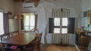 A rustic dining area with a wooden table and chairs, a radiator, and a window with shutters. - Rural house El Lucero, in the heart of the mountains (full rental) (Alájar)