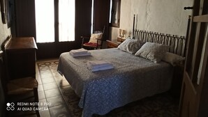 A bedroom with a bed, a chair, a nightstand, and a window with curtains. - Rural house El Lucero, in the heart of the mountains (full rental) (Alájar)