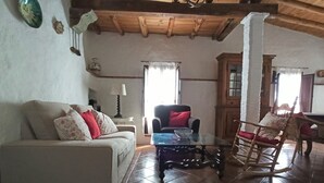A living room with a sofa, a glass coffee table, a rocking chair, and a wooden cabinet. - Rural house El Lucero, in the heart of the mountains (full rental) (Alájar)