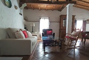 A living room with a sofa, a glass coffee table, a rocking chair, and a wooden cabinet. - Rural house El Lucero, in the heart of the mountains (full rental) (Alájar)