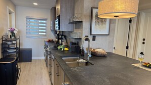 A modern kitchen with a large island, stainless steel appliances, and a pendant light. - Beachfront Studio right on the Sand! Ground Floor Newly Remodeled, Gulf View - M (Bradenton Beach)