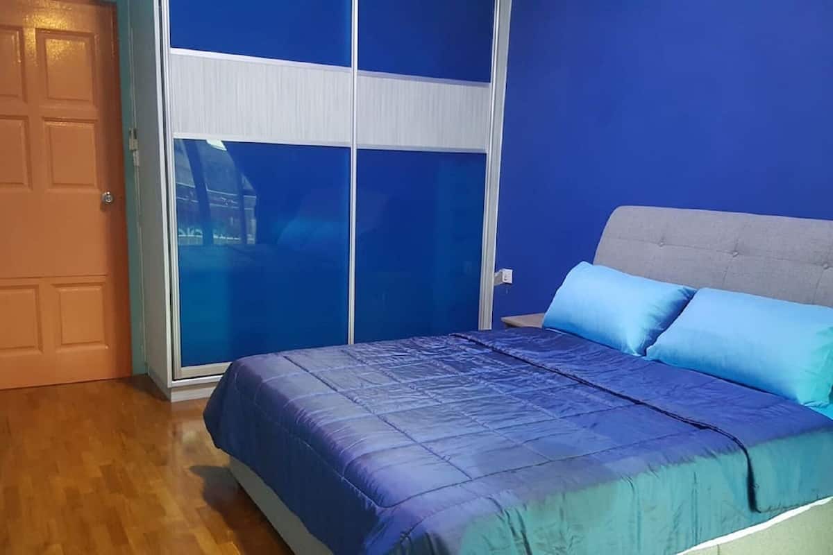 A bedroom with a bed, a grey headboard, and a blue wall.