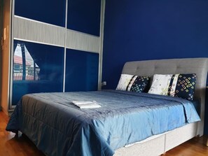 A bedroom with a bed, blue bedding, and patterned pillows. - Seladah Stay (Kuching)