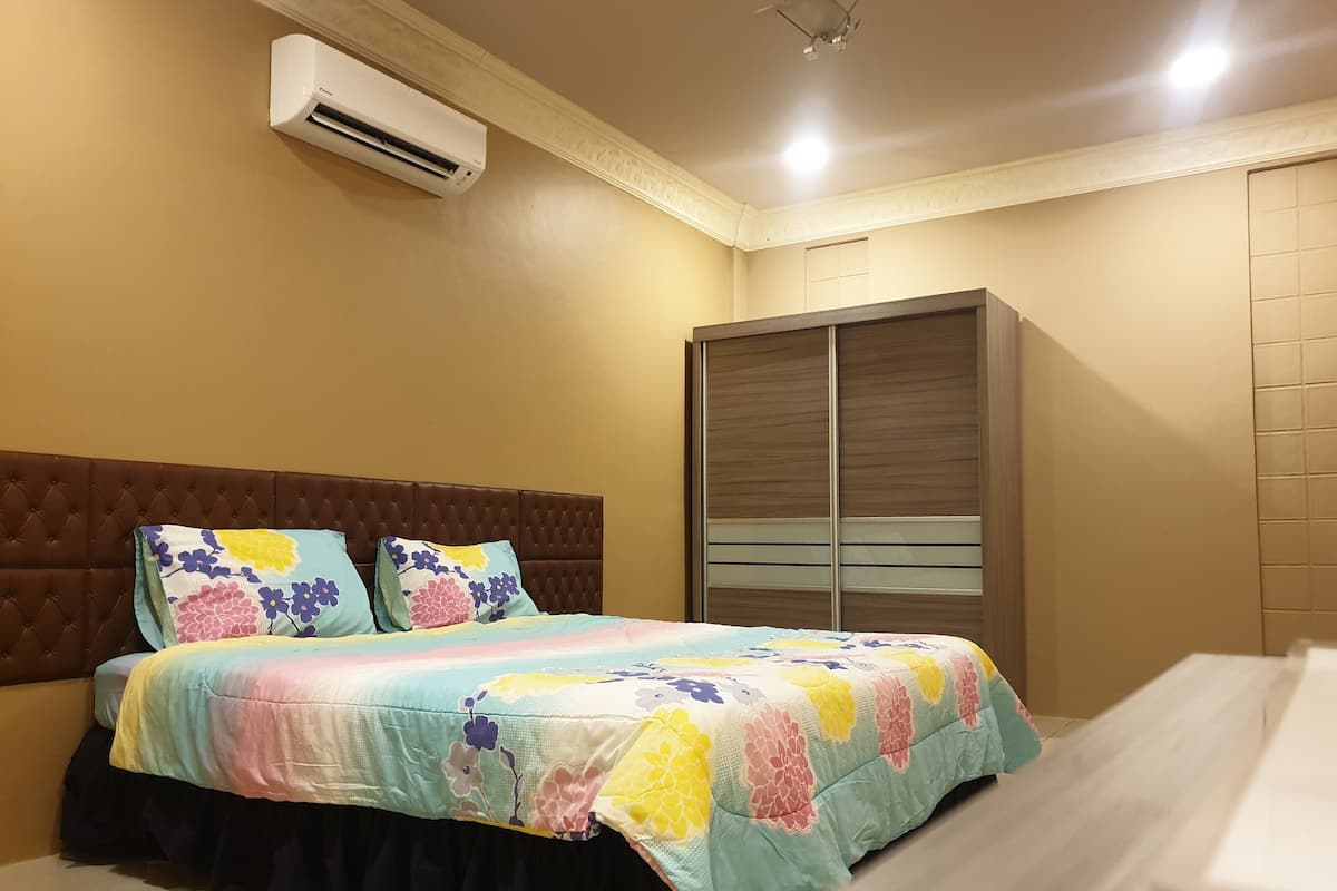 A bedroom with a bed, a wardrobe, and an air conditioning unit.