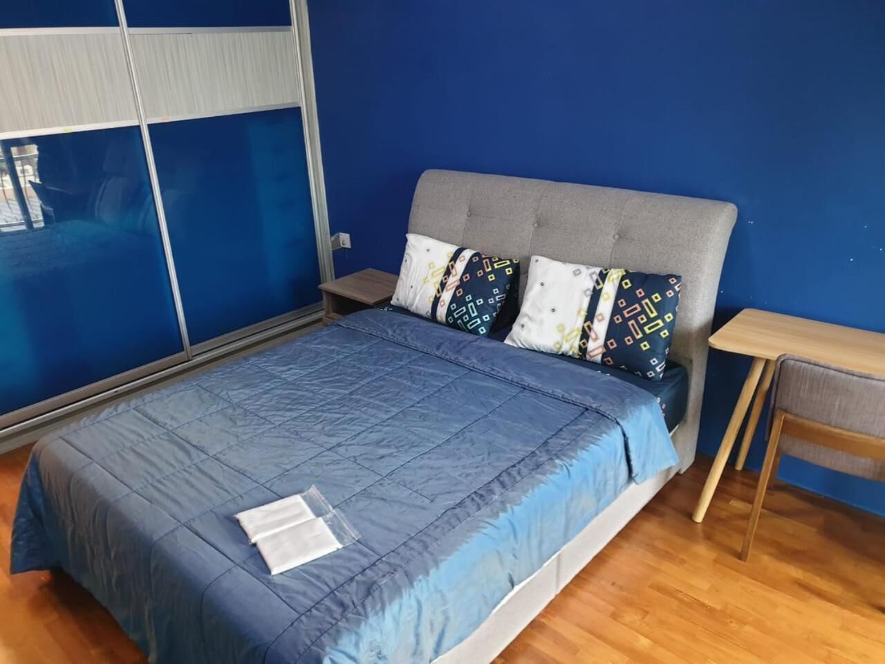 Une chambre à coucher avec un lit, des murs bleus et une fenêtre.