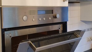 A modern kitchen with a built-in oven and a stainless steel range hood. - Housing for expats and companies (Arcelor Mittal, Volvo, ...) (Lochristi)