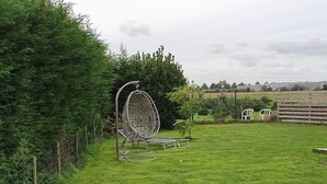 A grassy outdoor area with a metal egg chair, a small table, and a wooden fence. - Housing for expats and companies (Arcelor Mittal, Volvo, ...) (Lochristi)