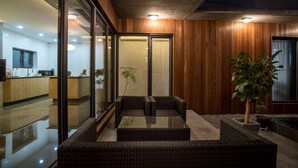 A modern kitchen with wooden cabinets, a glass dining table, and a seating area with wicker furniture. - This is a modern design space, and you can enjoy outdoor bath facilities (jeju)