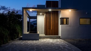 A modern building with a stone pathway leading to a wooden door. - This is a modern design space, and you can enjoy outdoor bath facilities (jeju)