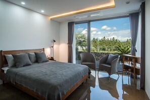 A modern bedroom with a large bed, a chair, and a balcony with a view of greenery. - This is a modern design space, and you can enjoy outdoor bath facilities (jeju)