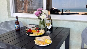 Ett bord dukat med en ölflaska, ett vinglas, en tallrik med ost, jordgubbar, hallon och en vas med blommor.