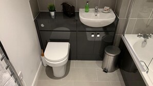 A modern bathroom with a toilet, sink, and trash bin. - Apt. 4 at the Belvedere (Wolverhampton)