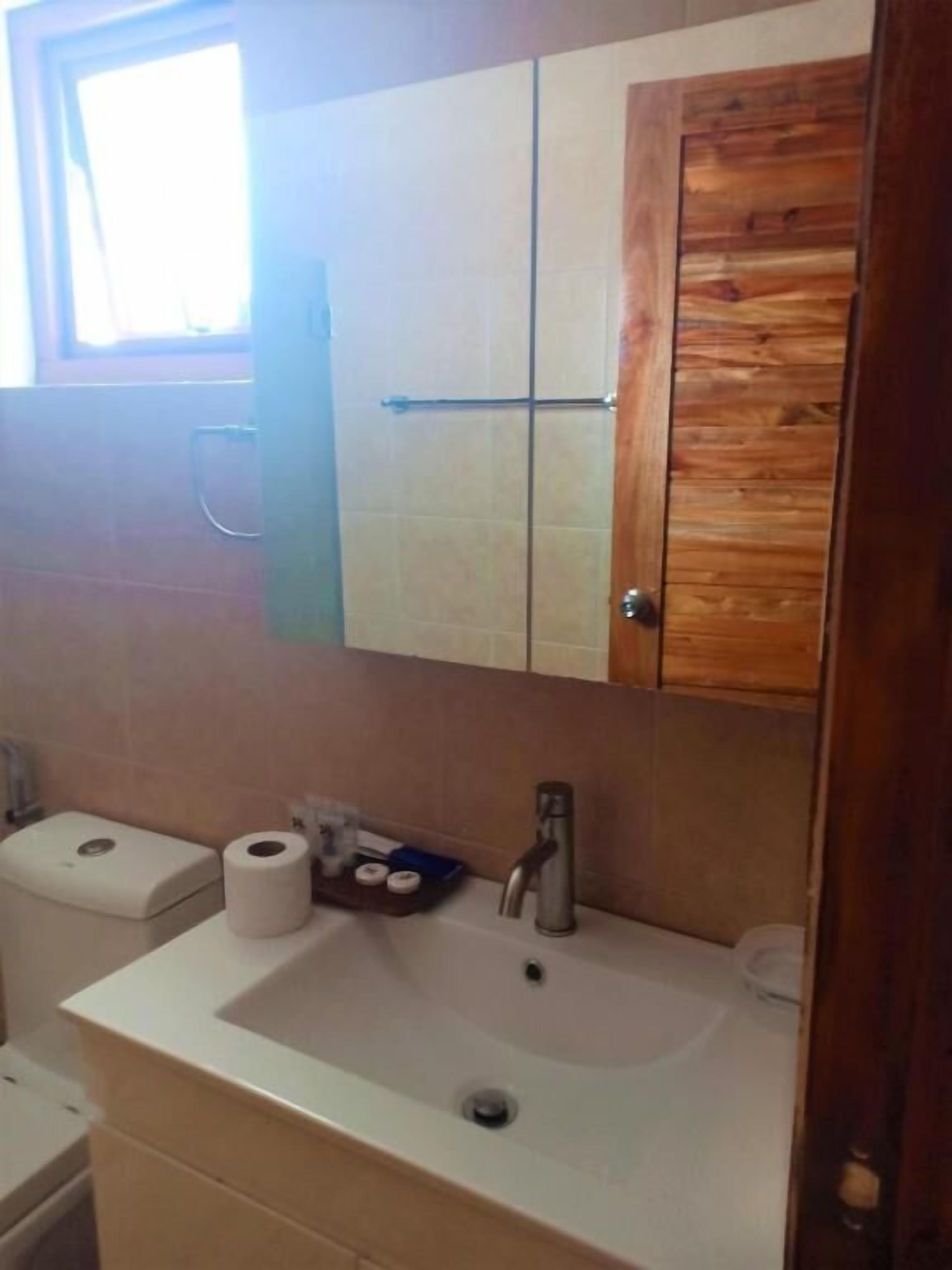A bathroom with a wooden vanity, a sink, and a toilet.