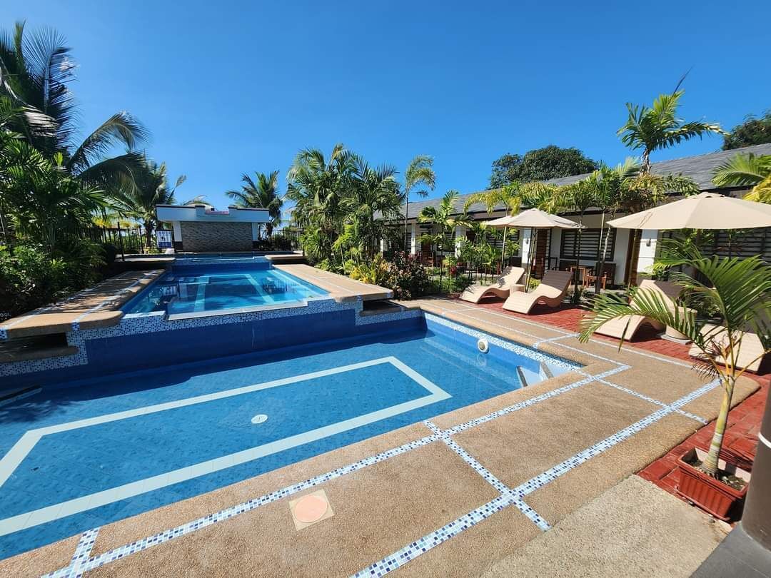 Une piscine avec une terrasse carrelée, des chaises longues et des parasols.