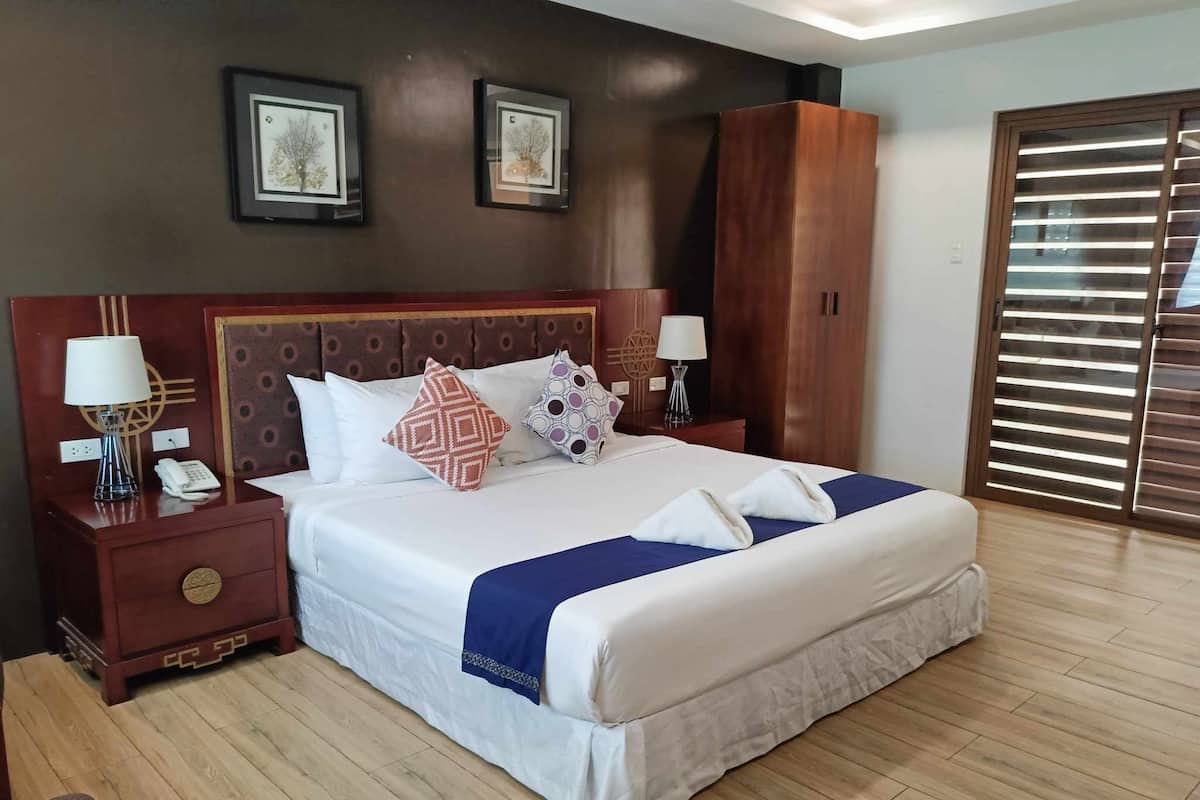 A neatly made bed with a blue accent, a wooden headboard, and two bedside tables with lamps and a phone.