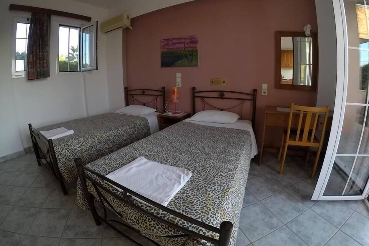 Ein Zimmer mit zwei Betten, einem Schreibtisch und einem Stuhl.