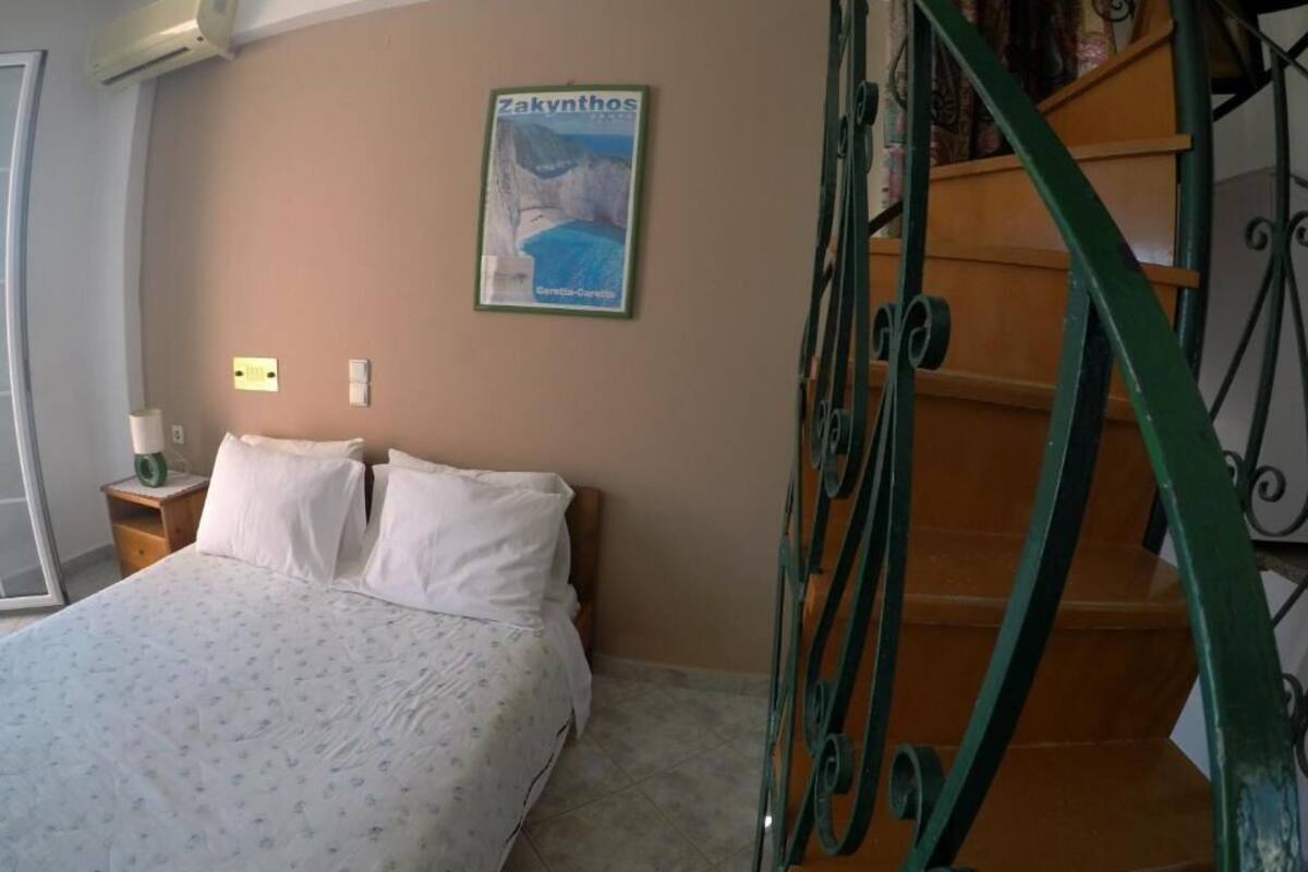 Ein Schlafzimmer mit einem Bett, einem Bild an der Wand, einem Nachttisch und einer Treppe.