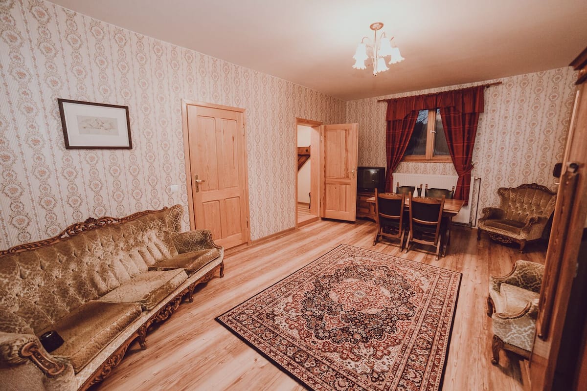 A traditional living room with a vintage sofa, a patterned rug, and classic wooden furniture.