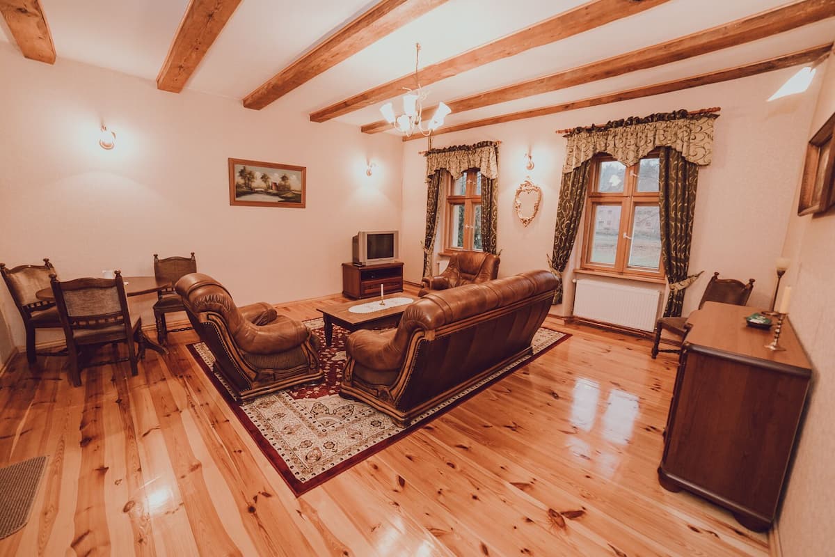 A cozy living room with wooden floors, a leather sofa, and a dining table.