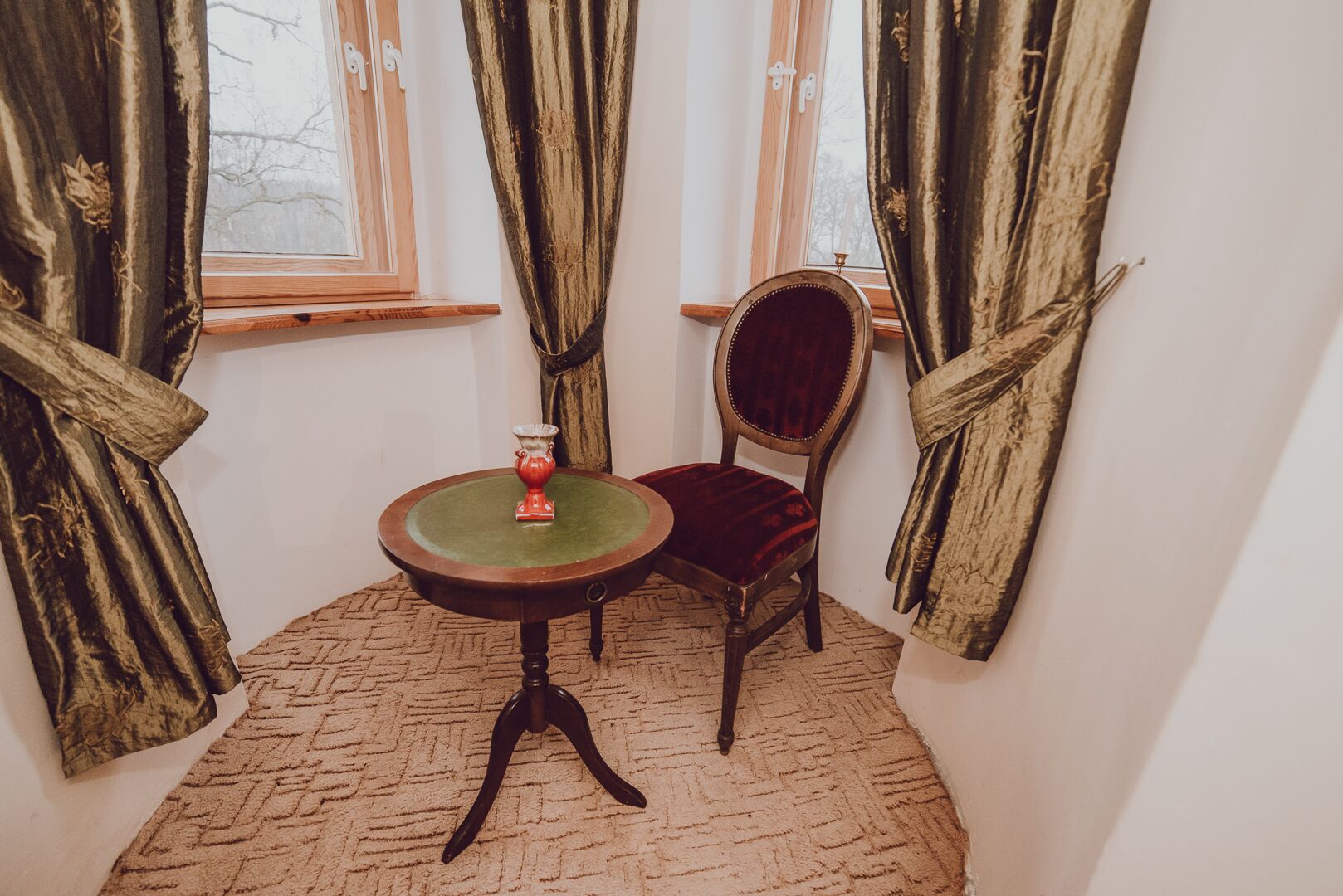 Una habitación con una mesa redonda, una silla y una ventana con cortinas.
