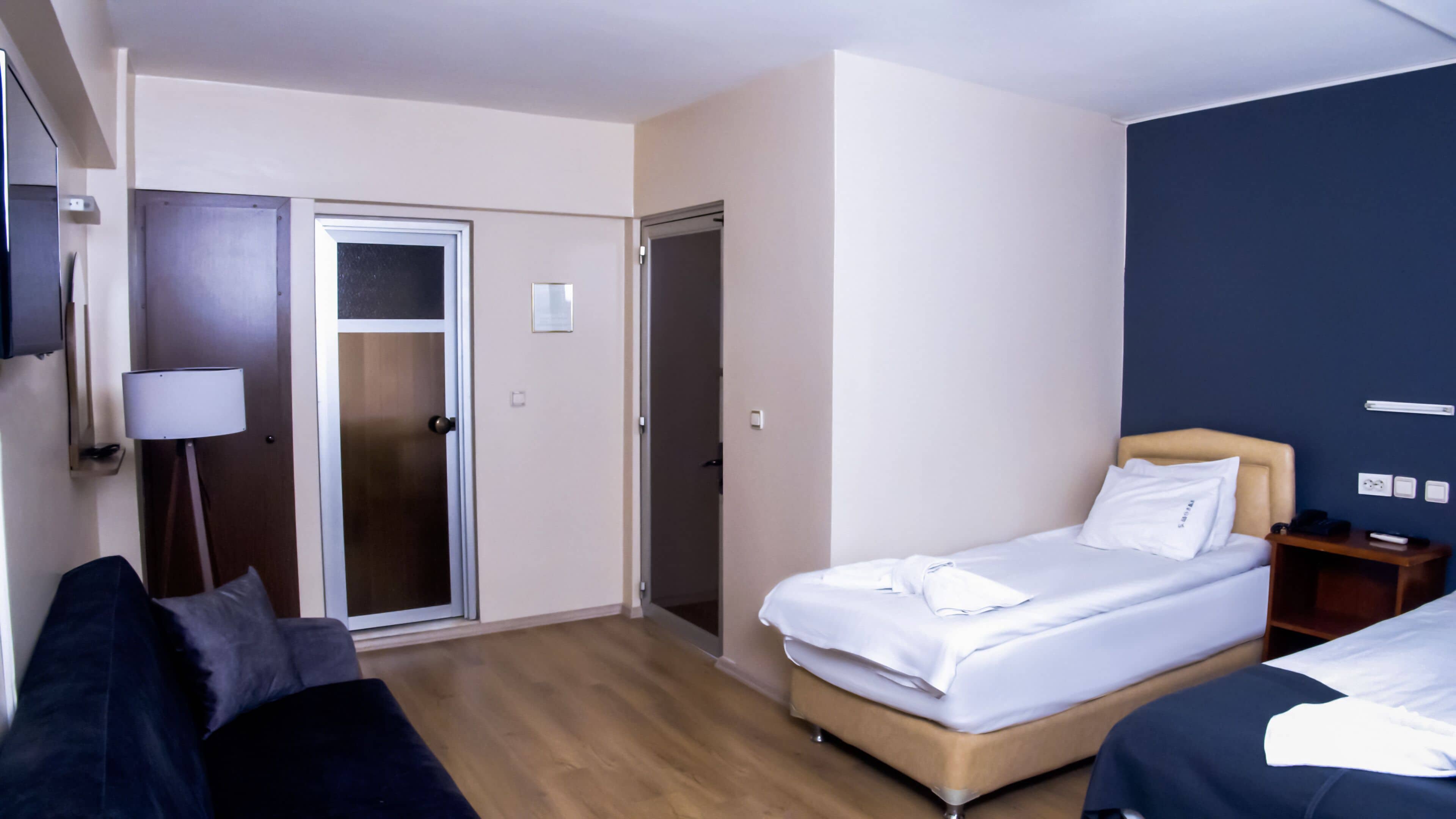Et hotelværelse med seng, sofa, skrivebord og dør.