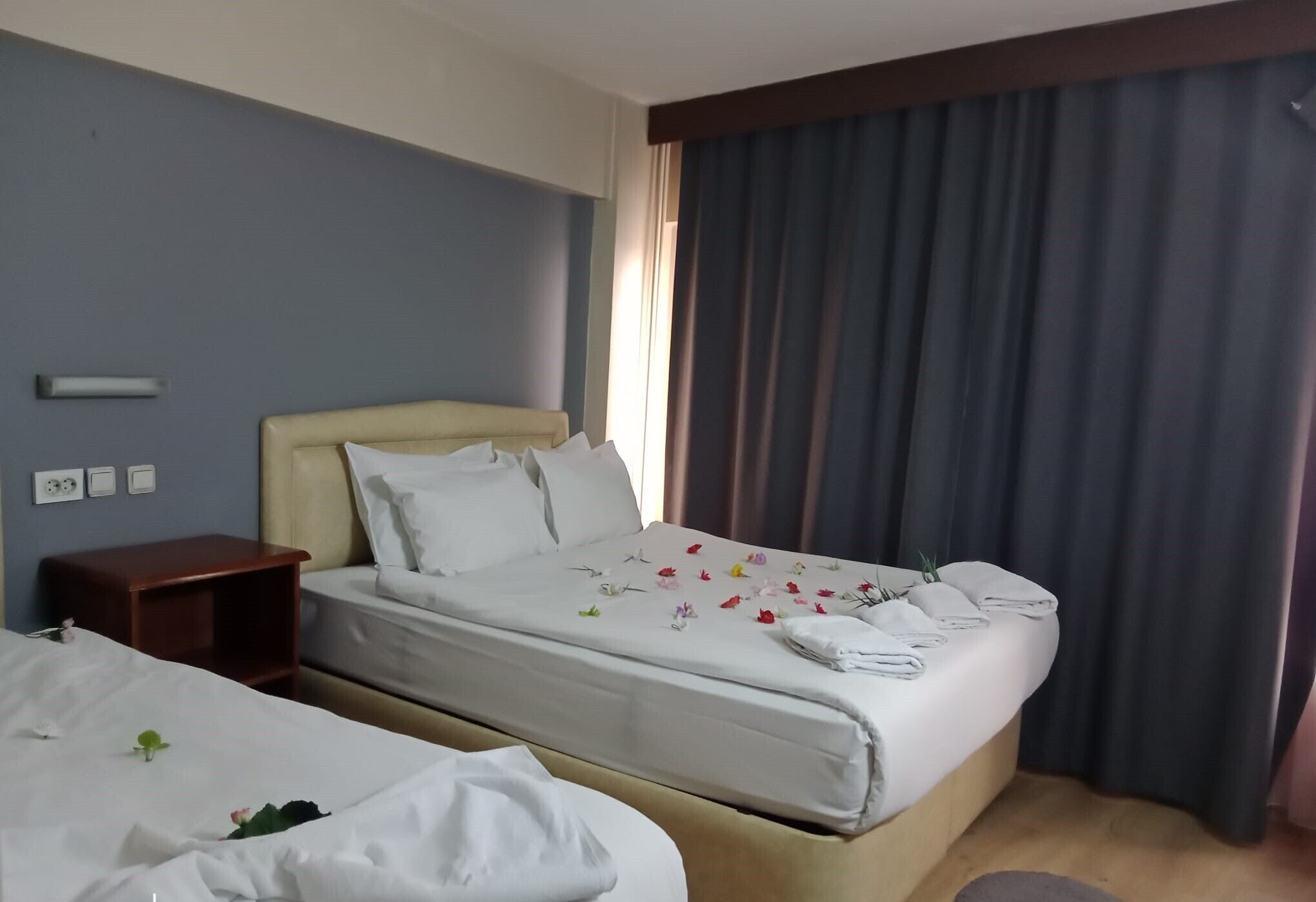 A hotel room with two beds, a nightstand, and a window with curtains.