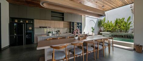 A modern kitchen with a wooden ceiling, built-in cabinets, and a large island with bar stools.
