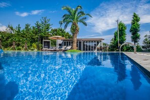 A swimming pool with lounge chairs and a modern house with large windows.