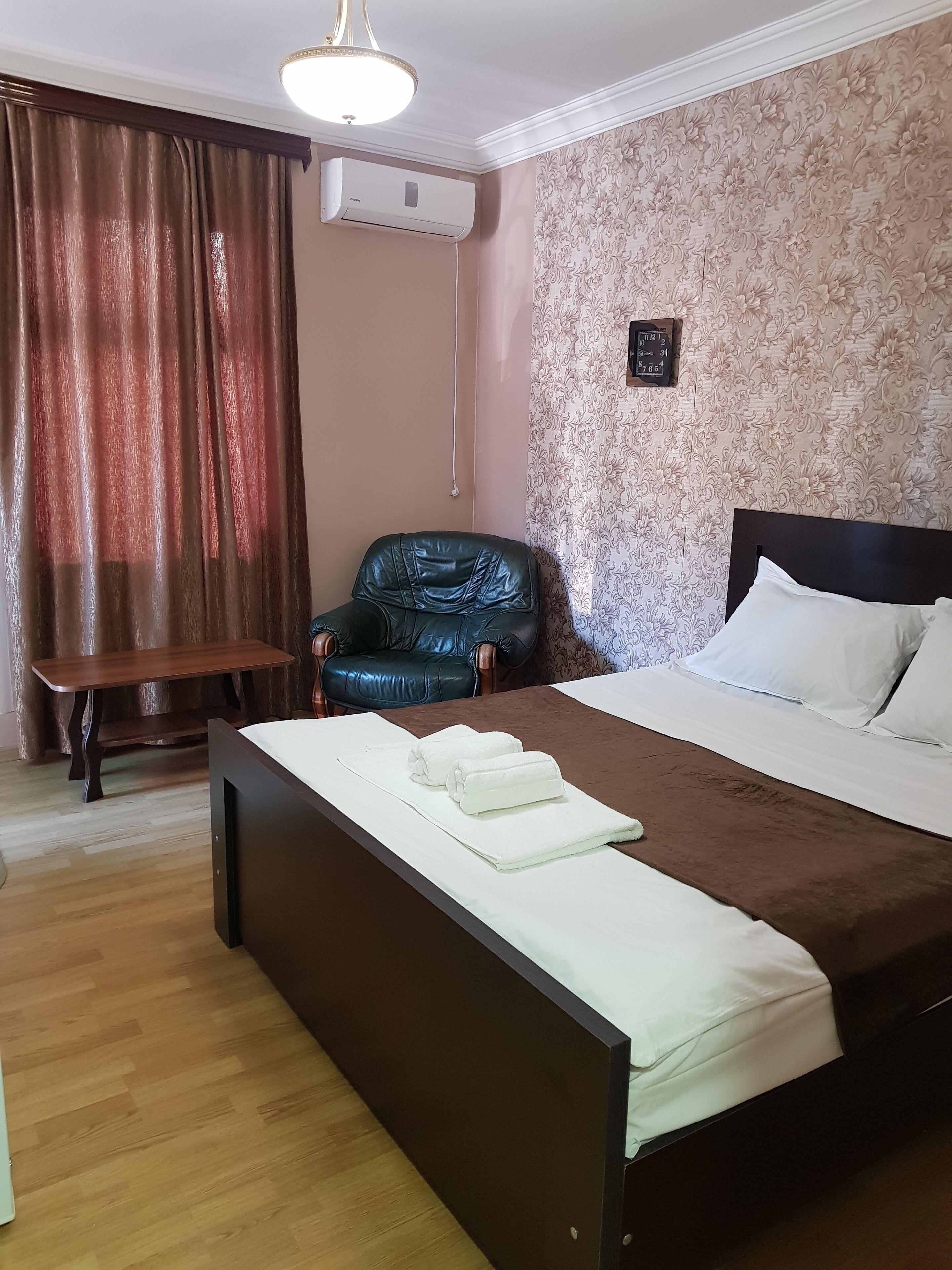 A neatly arranged bedroom with a bed, a chair, a table, and an air conditioning unit.