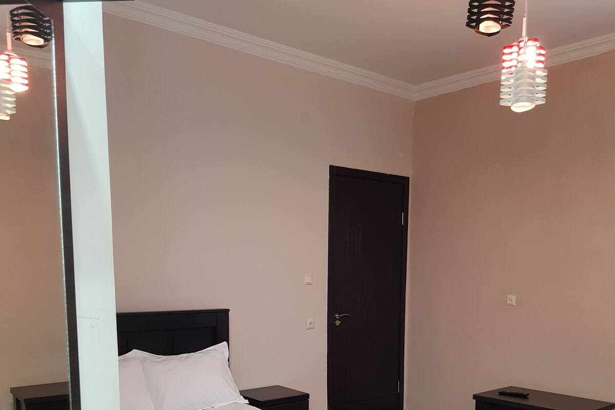 A bedroom with a four-poster bed, bedside tables, a wardrobe, and a door.