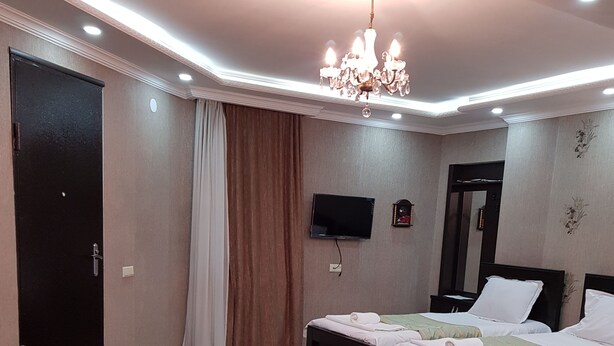 Habitación de hotel con dos camas, un televisor, una araña y un sillón de cuero.