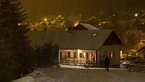 A snow-covered landscape with a building featuring a balcony and a person walking away.
