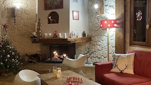 A cozy living room with a fireplace, a Christmas tree, and a red sofa.
