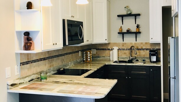 A modern kitchen with white cabinetry, a central island with stools, a microwave, and a coffee maker. - Private studio; big outdoor space  (Orlando)