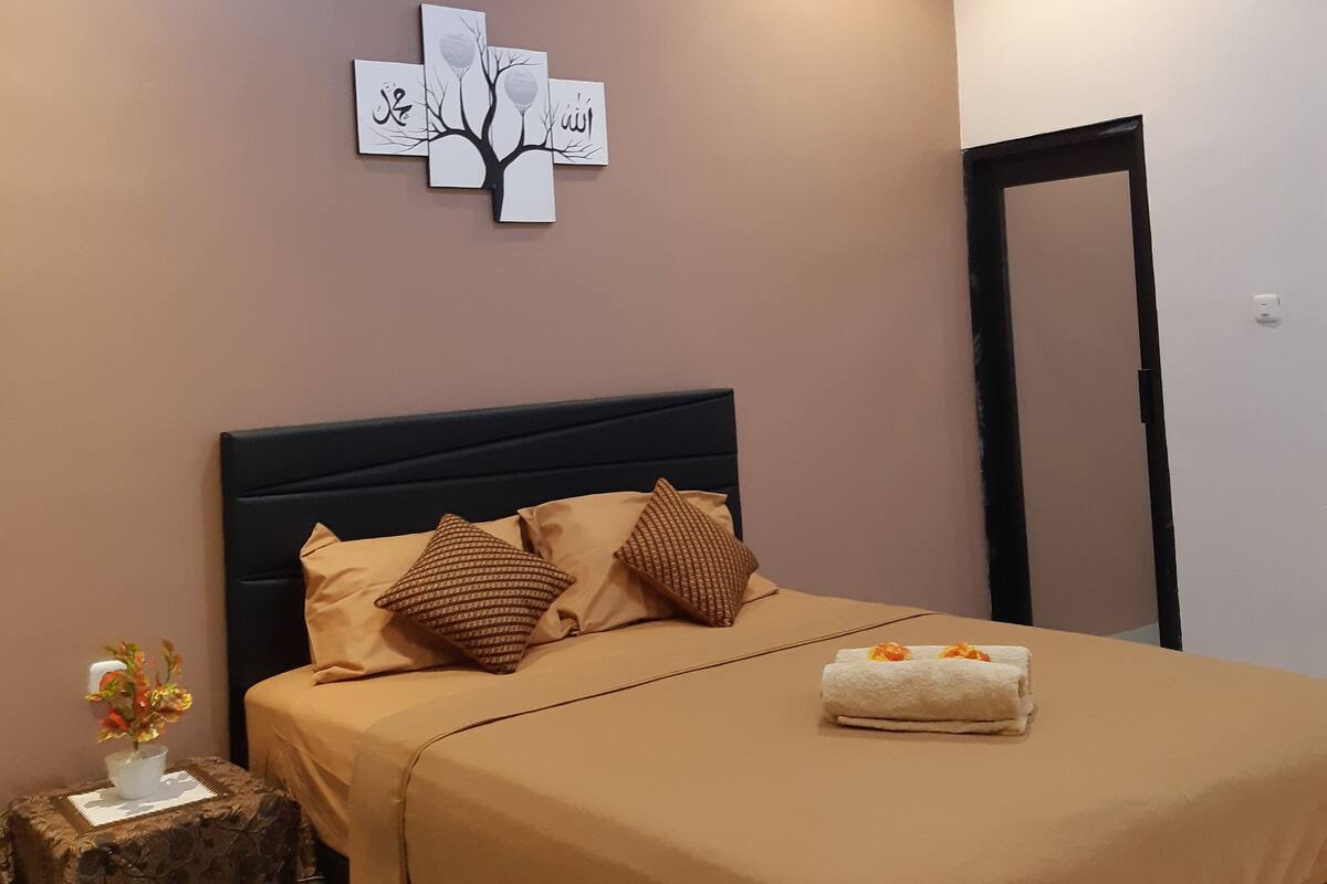 Un dormitorio con una cama, una mesita de noche, una obra de arte en la pared y una lámpara de techo.