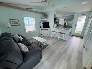 A modern living room with a grey sofa, a white coffee table, and a ceiling fan.