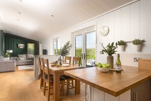 A dining area with a wooden table, chairs, and a view through glass doors to the outdoors. - Diamond Lodge - Hot Tub - Free WiFi & Parking - Pets Welcome (Cheddar)
