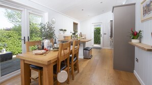 A bright kitchen with wooden furniture, a dining table, and a view of greenery outside. - Diamond Lodge - Hot Tub - Free WiFi & Parking - Pets Welcome (Cheddar)